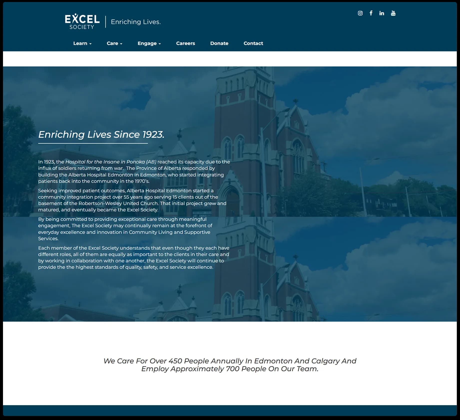Excel Society’s initial About page, featuring a semi-transparent overlay of a red-brick church behind text titled ‘Enriching Lives Since 1923,’ followed by a multi-paragraph history.
